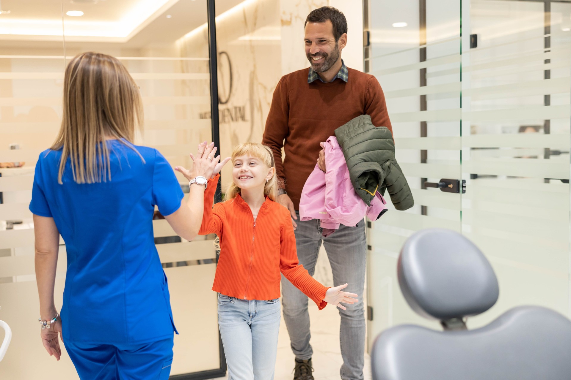 Happy child high-fives dentist in modern dental office.