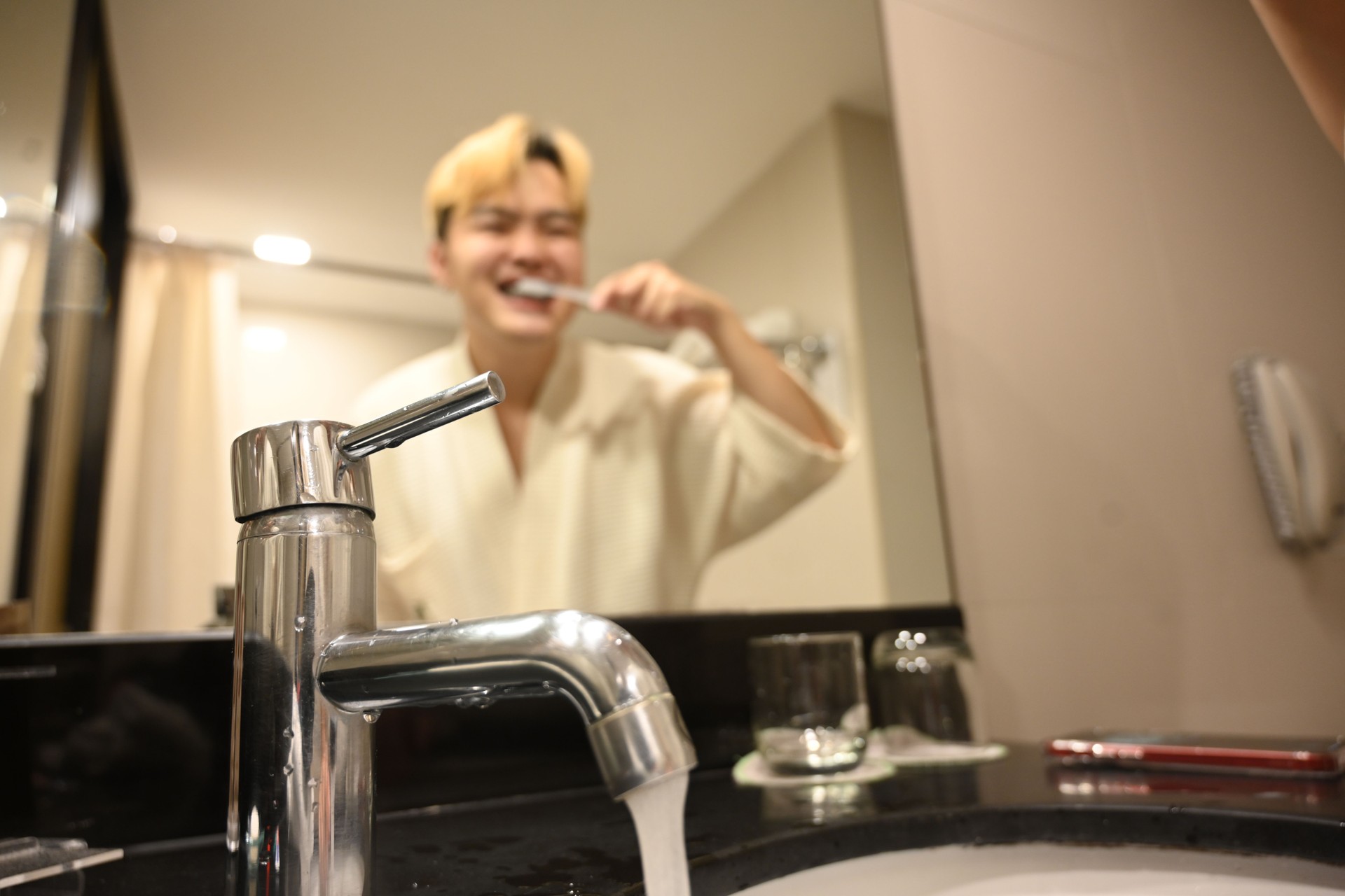 Close-up of a faucet left open while a man brushing his teeth, Campaign to save water by turning off faucets while brushing to conserve water and support sustainable living